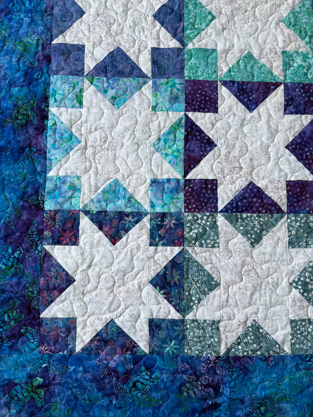 Detail shot of batik sea turtle fabric squares in patchwork quilt