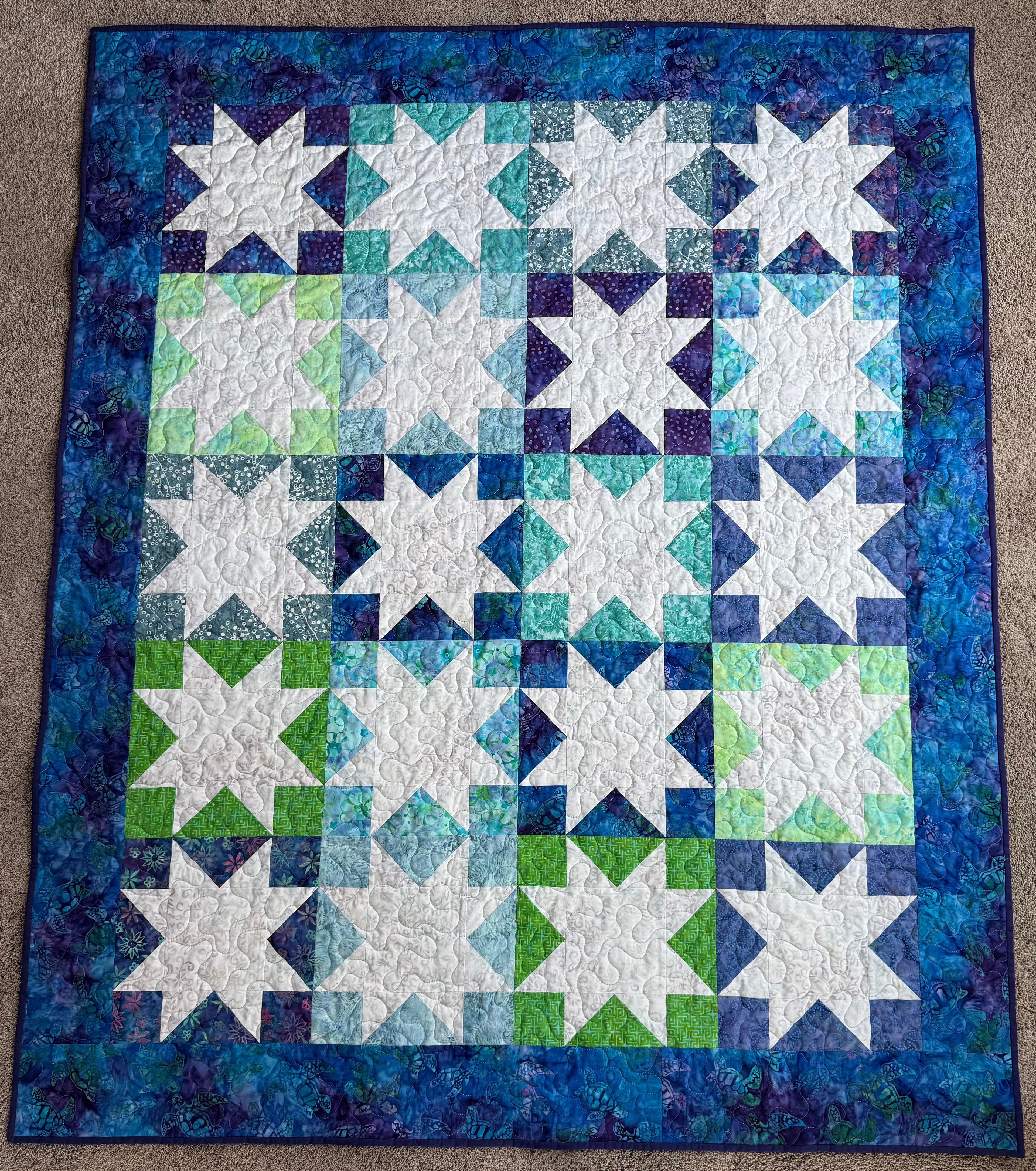 Full view of handmade sea turtle batik quilt on neutral background
