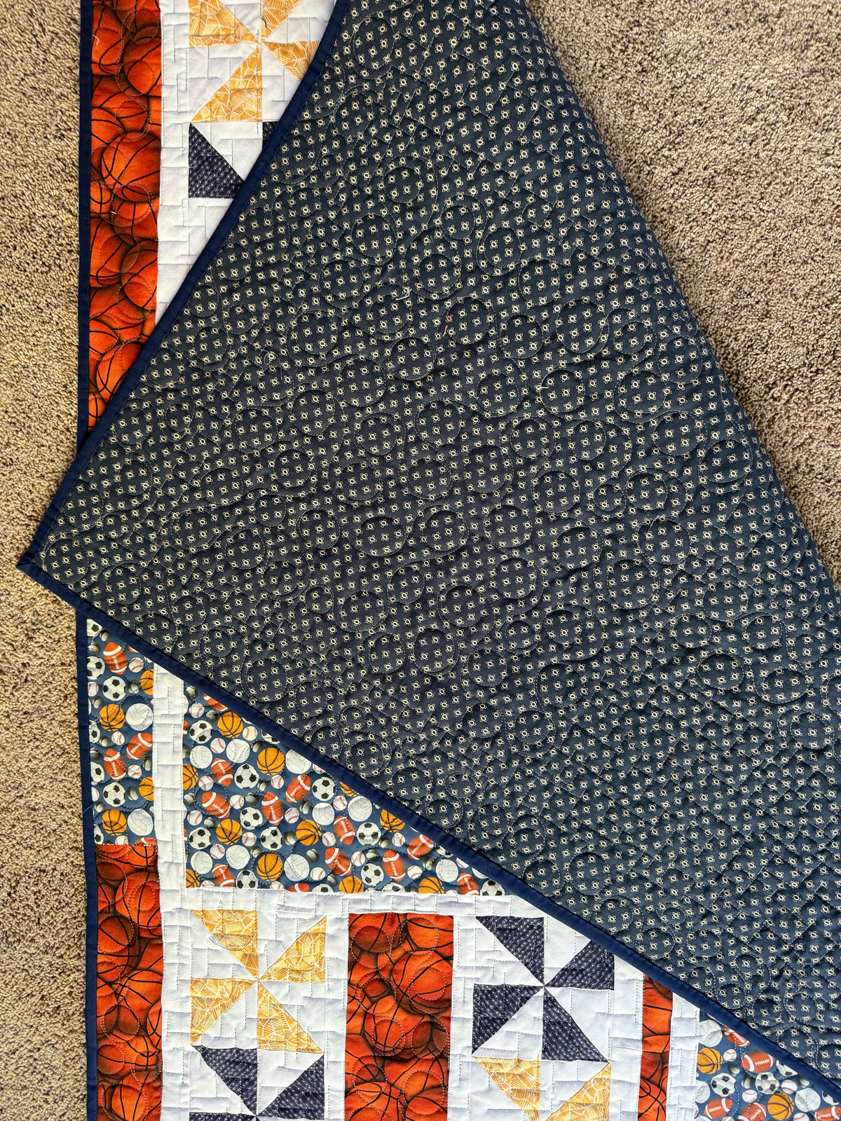 Handmade sports quilt showing backing fabric in a navy blue print