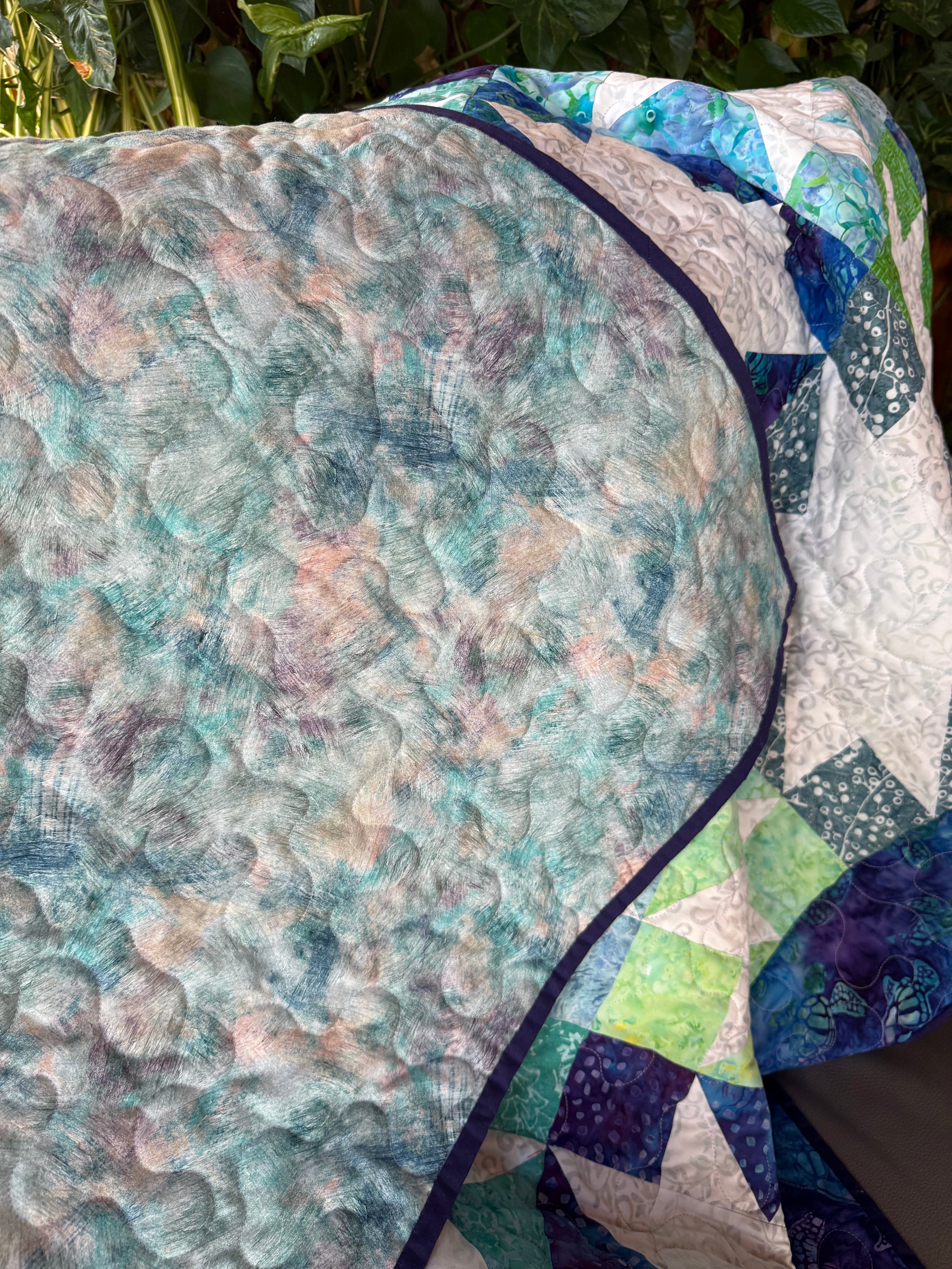 Handmade ocean-themed quilt draped over chair — throw size