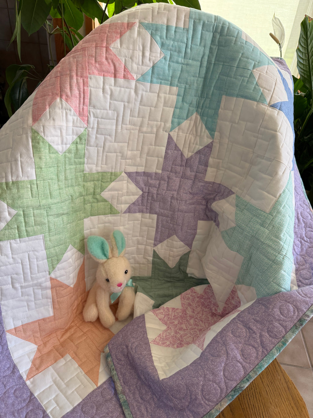 Handmade baby quilt in soft pastel stars with close up of quilting