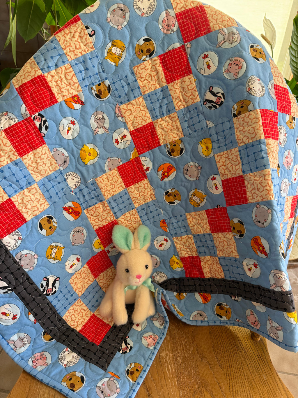 Colorful handmade baby quilt with farm animals in blue and red fabrics