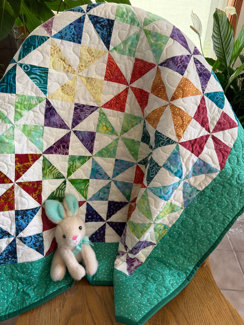 Colorful baby quilt in a pinwheel pattern using batik fabrics