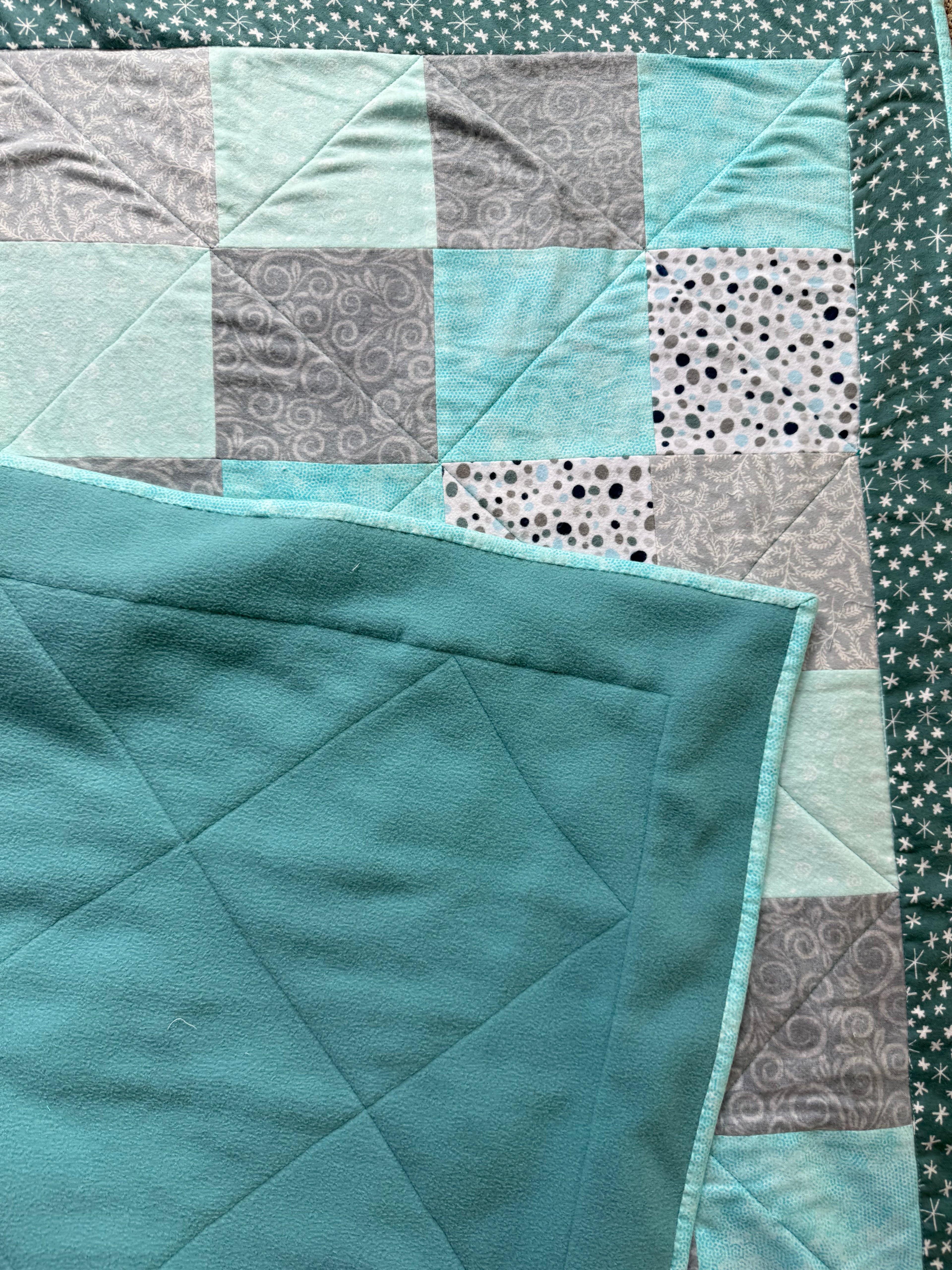 Handmade flannel scrap quilt in mixed prints, cozy and colorful, by Oak & Thread Quilts.  Backing is soft teal fleece.