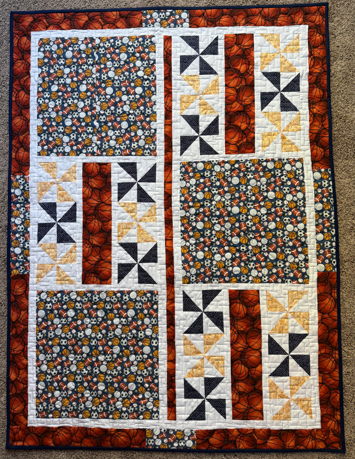 Handmade quilt featuring balls for various sports in navy blue and orange
