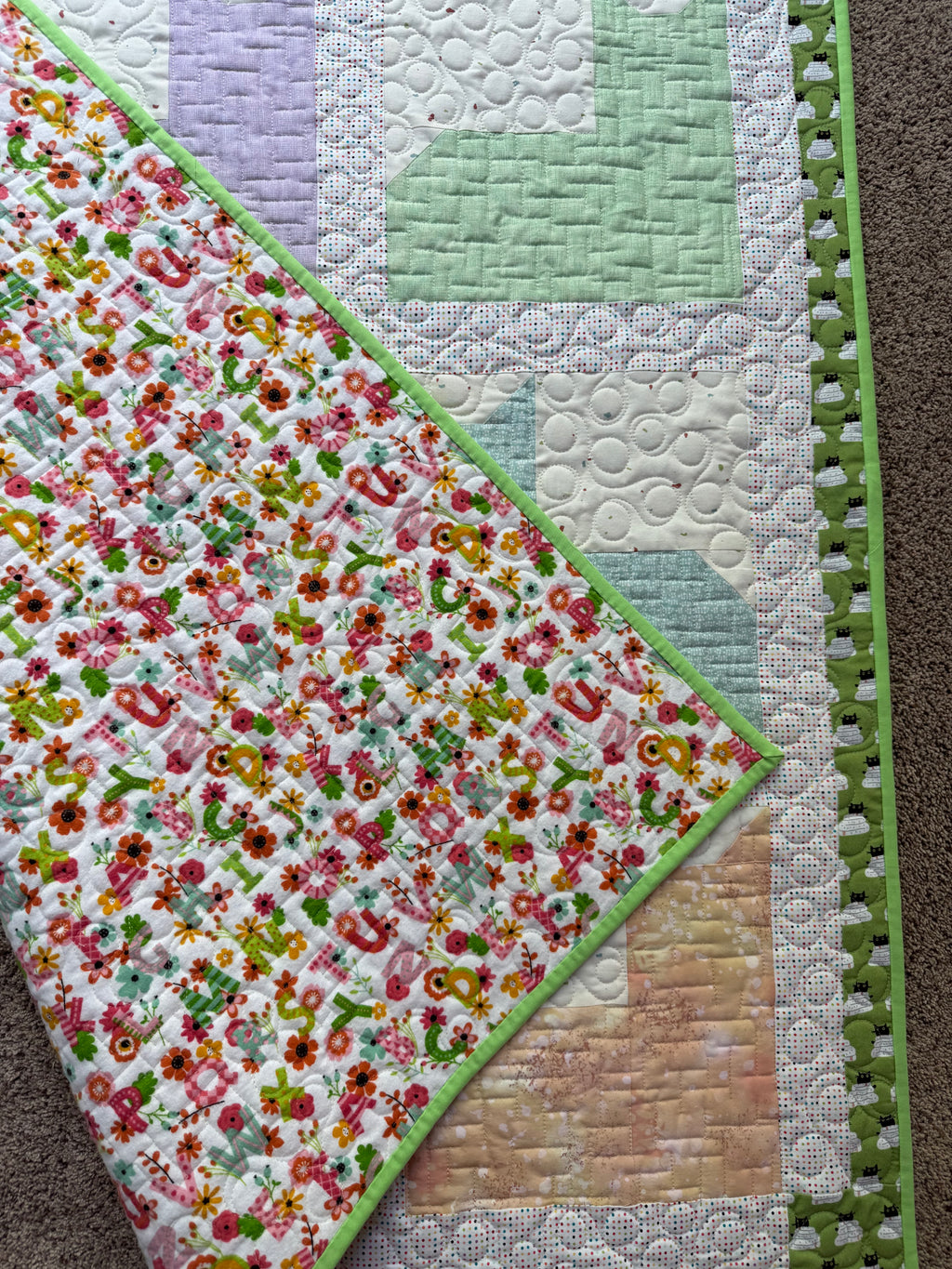 Handmade cat quilt showing backing in a flannel alphabet print