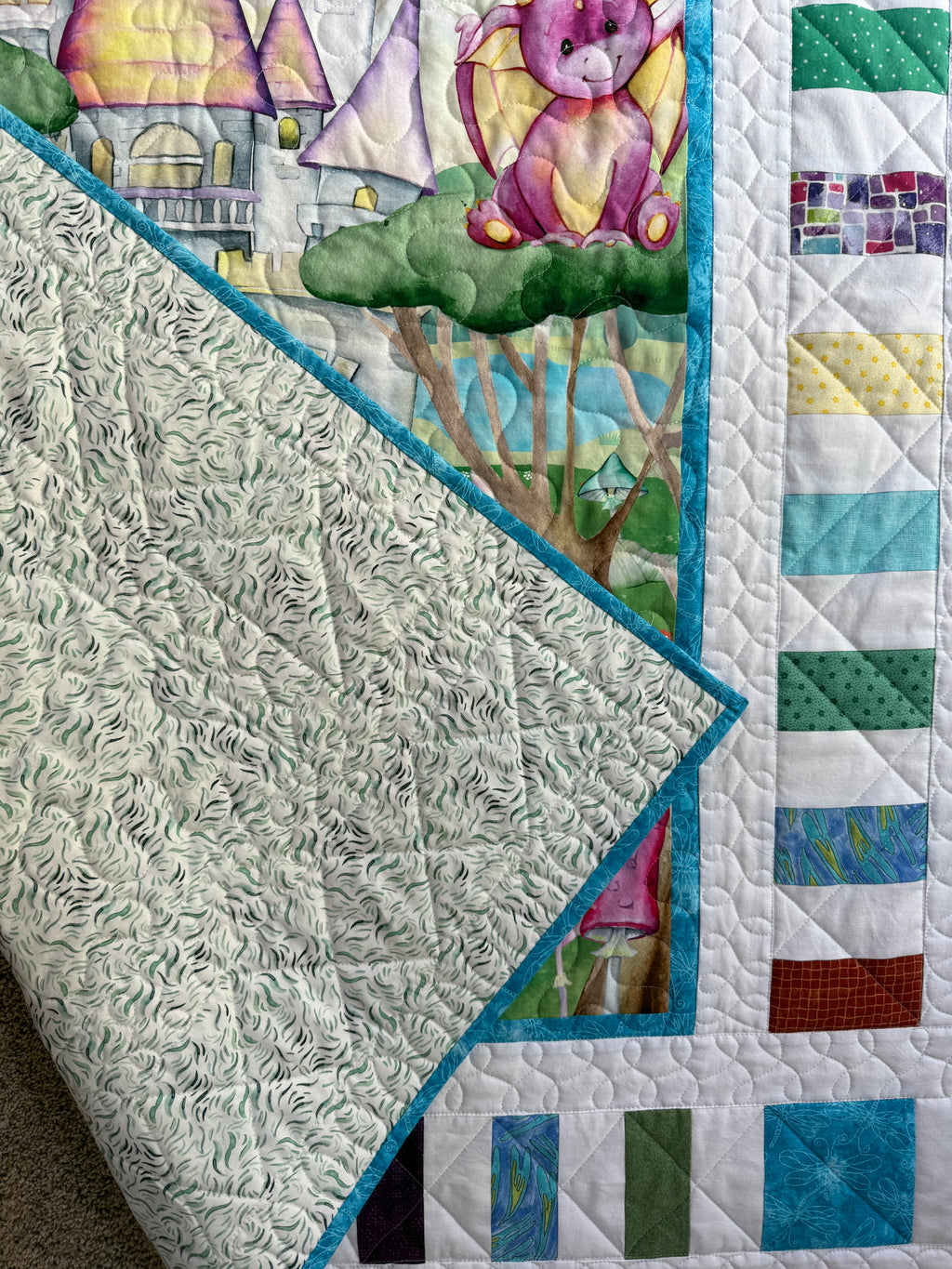 Handmade baby dragon quilt with colorful dragon design, soft cotton fabric and printed blue and green backing, made by Oak & Thread Quilts