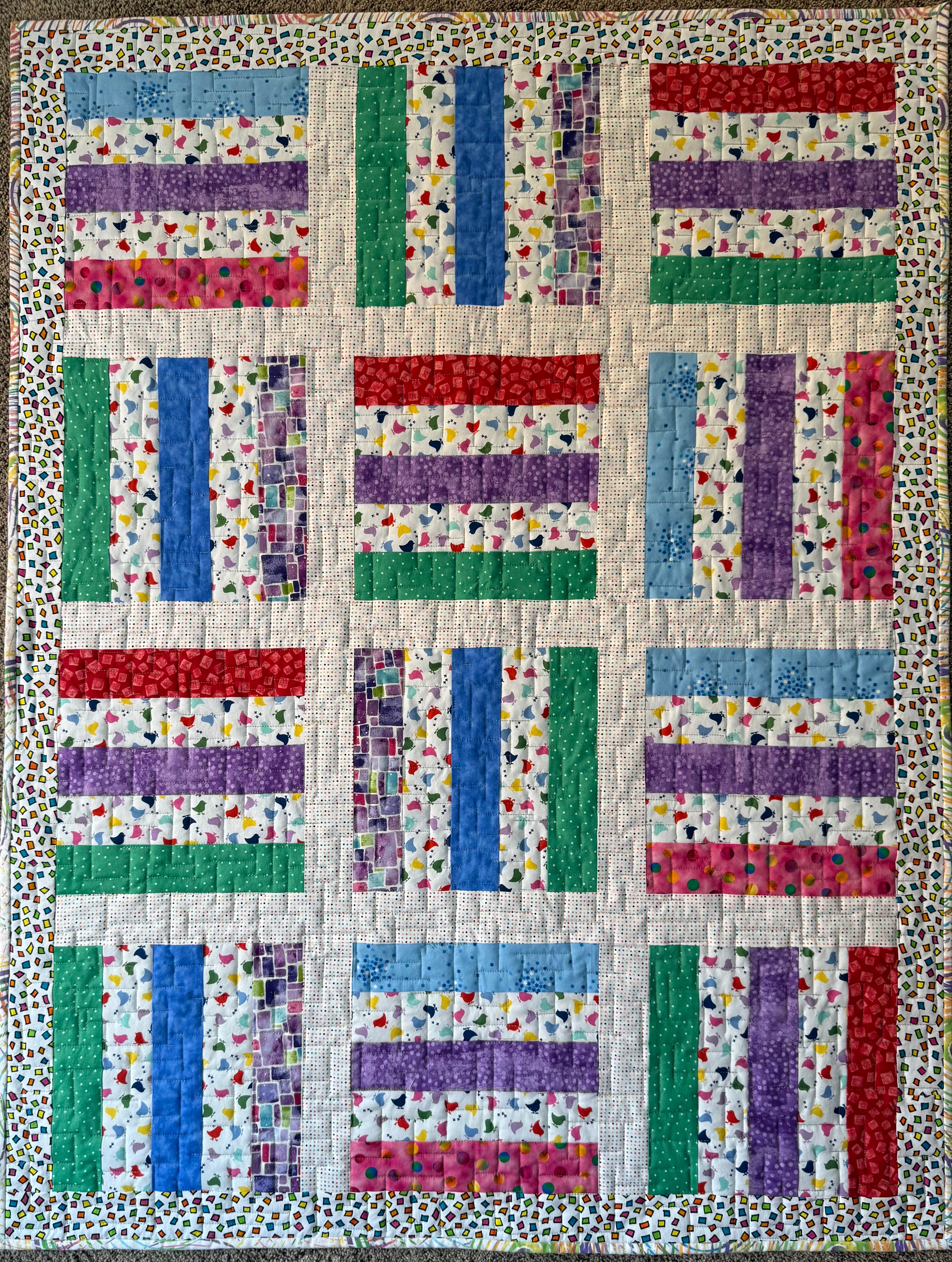 Colorful baby quilt using various strips of fabrics featuring baby chicks