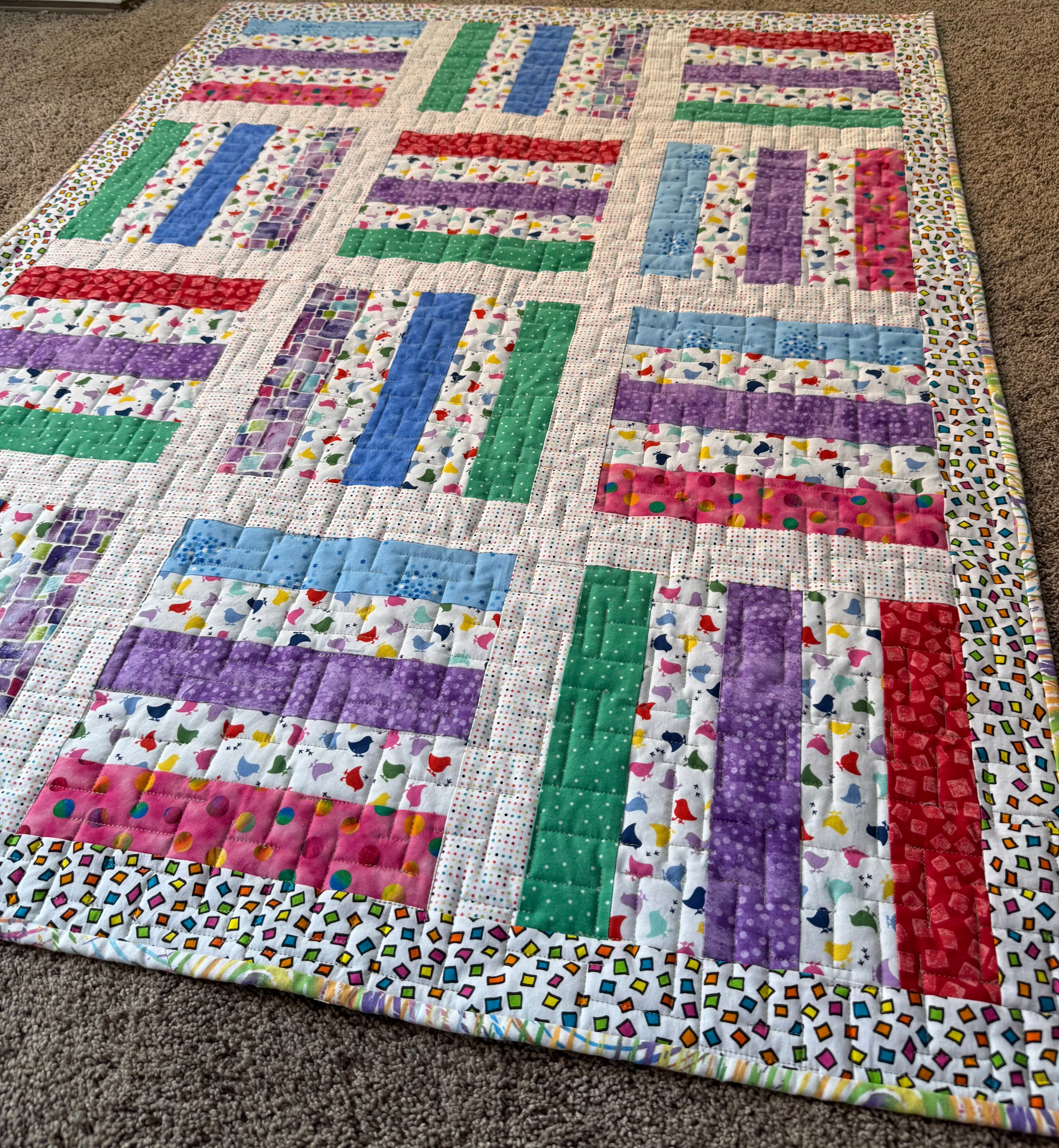 Colorful baby quilt with various color fabric strips 
