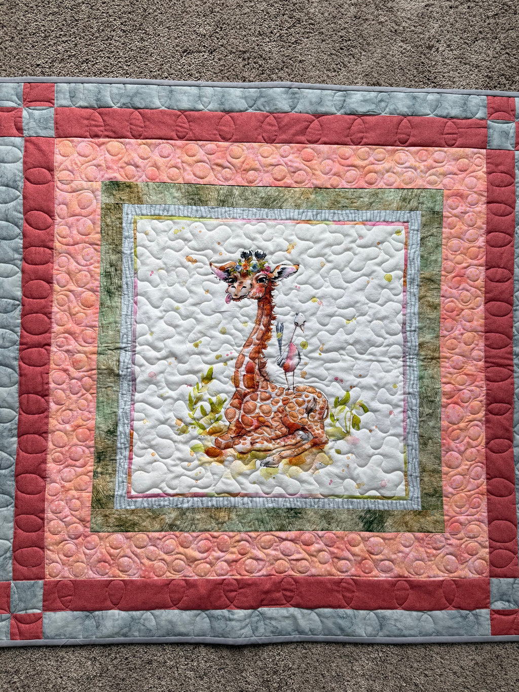 Baby quilt with giraffe panel surrounded by borders