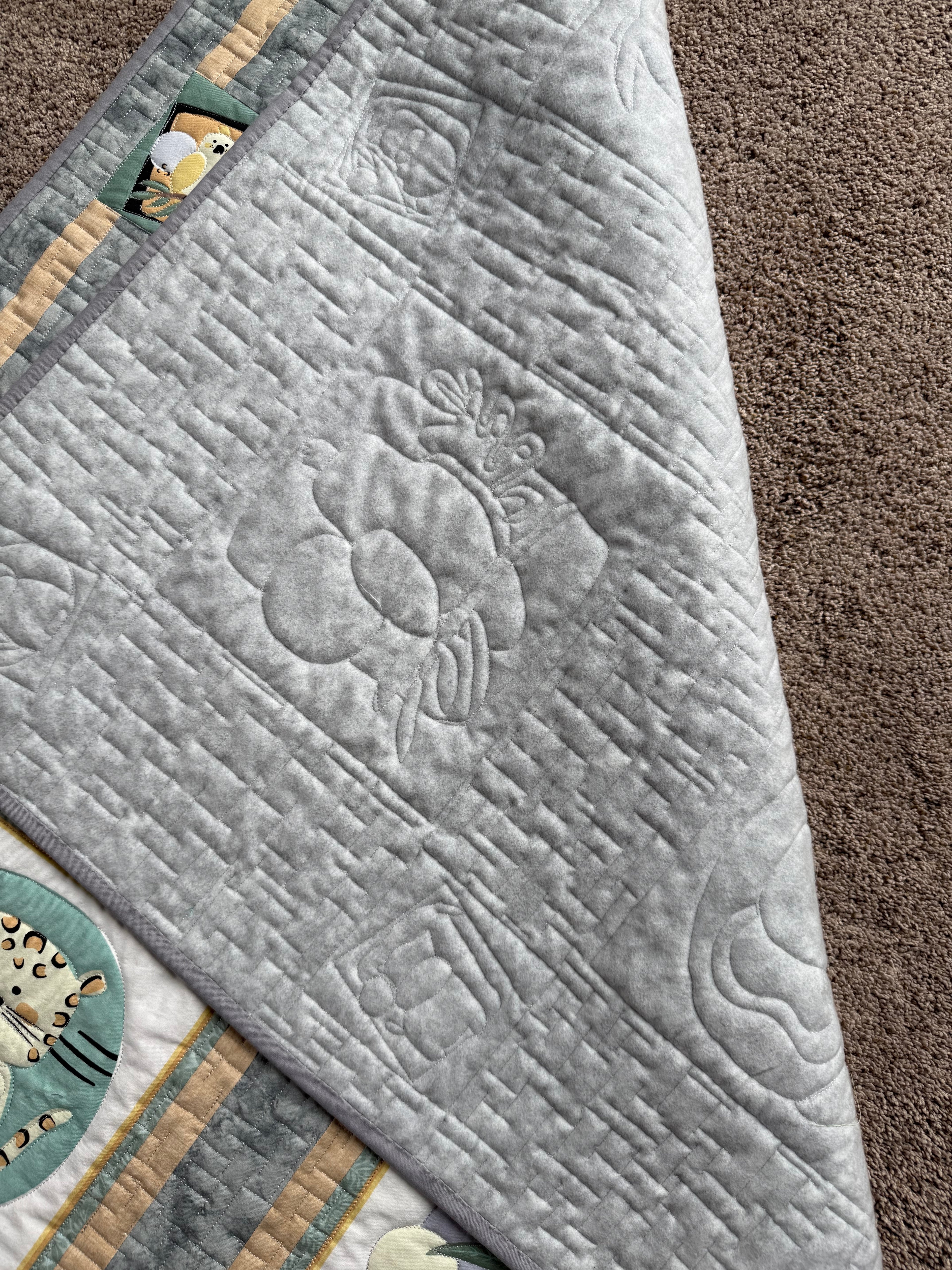 Handmade jungle quilt showing gray backing fabric and quilting 
