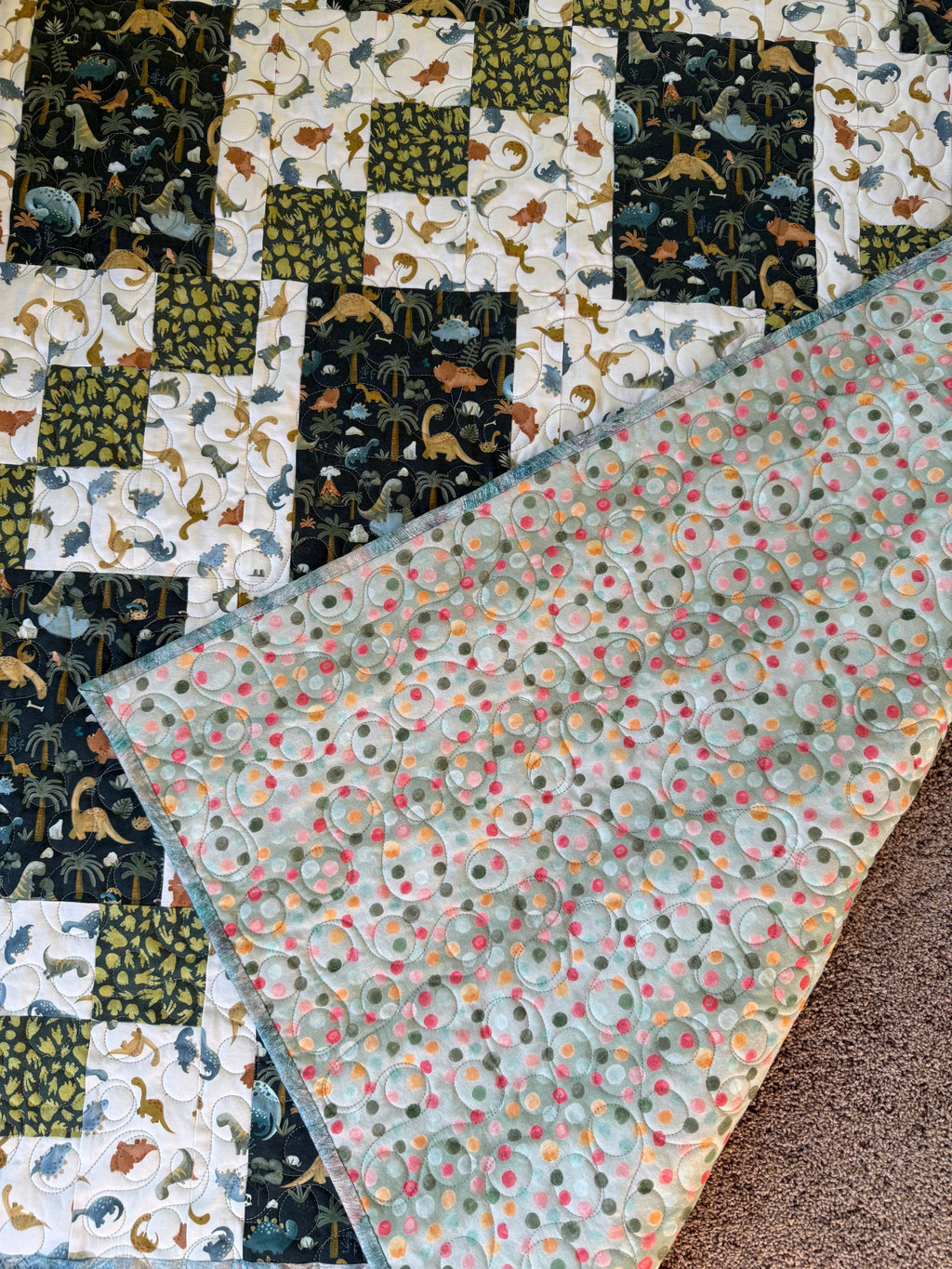 Handmade dinosaur quilt showing green dotted backing fabric 