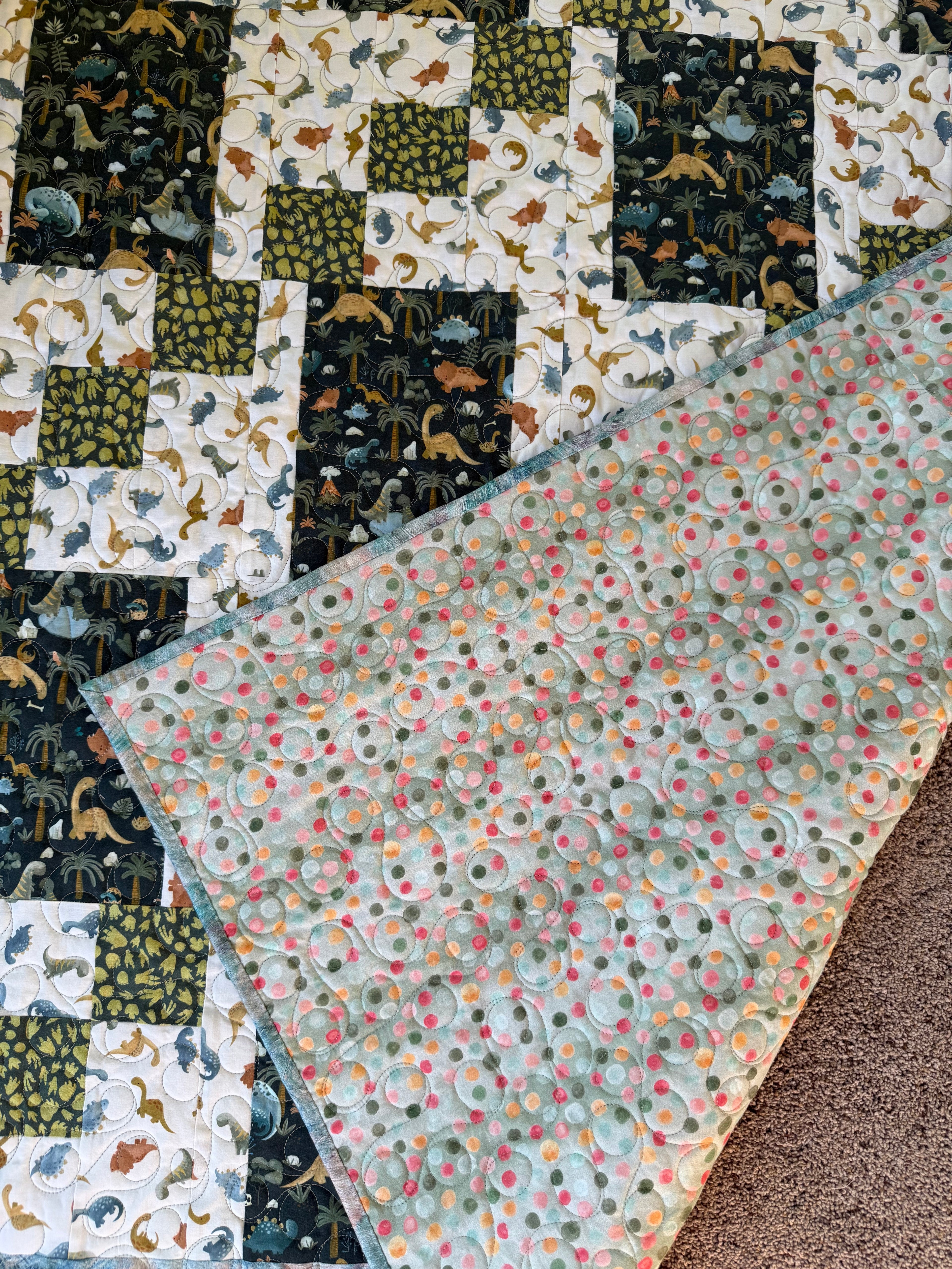 Handmade dinosaur quilt showing green dotted backing fabric 
