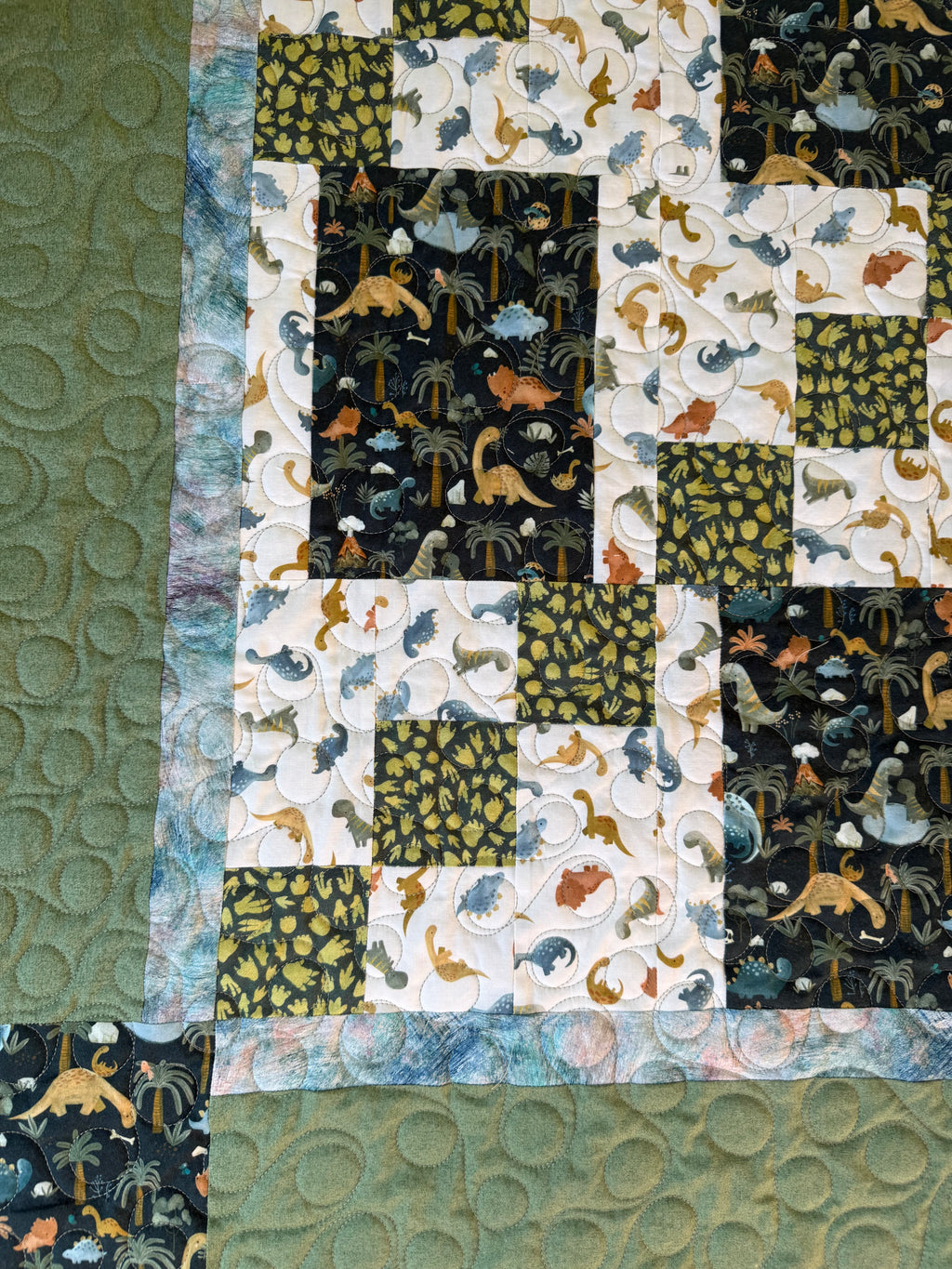 Handmade dinosaur quilt showing close up of dinosaur prints