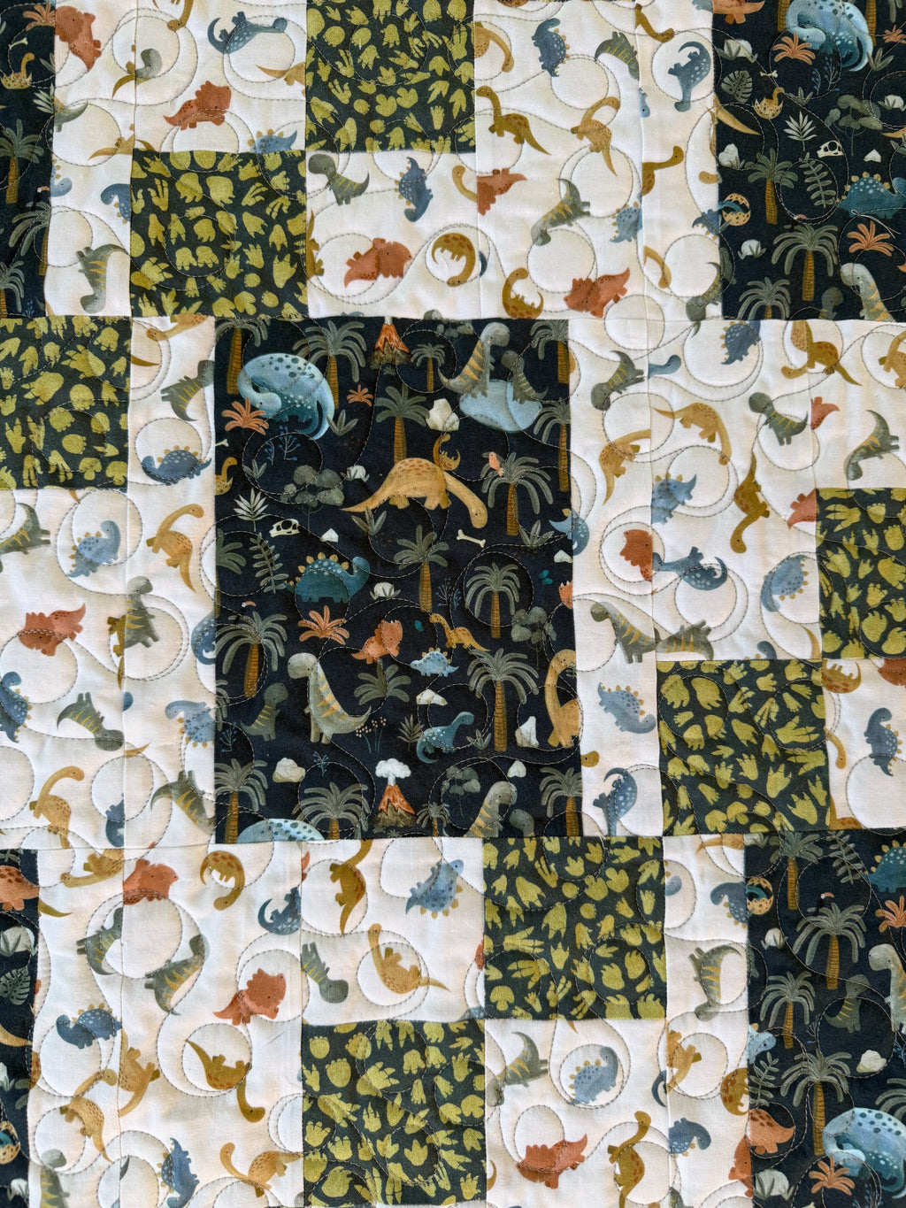Handmade dinosaur quilt showing close up of dinosaur prints 
